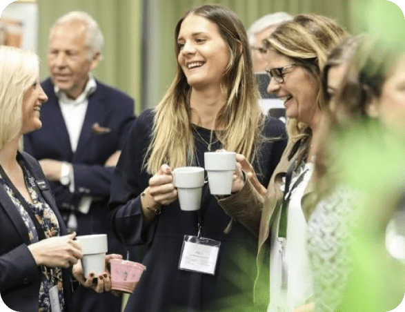Tre kvinnor håller i varsin kaffekopp och pratar